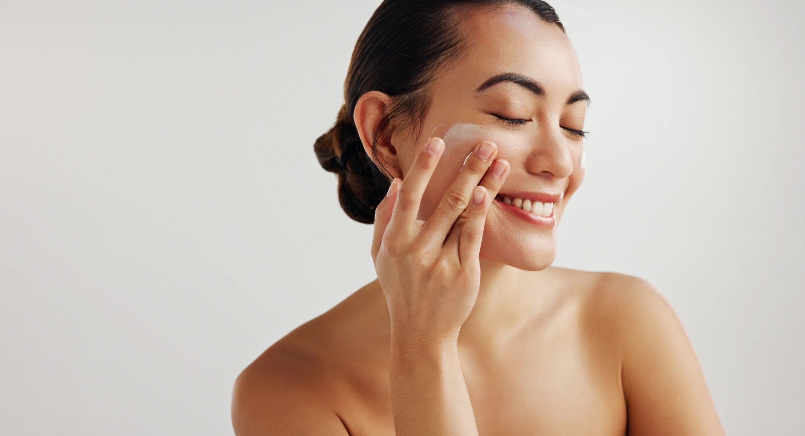 Woman applying skincare lotion in studio